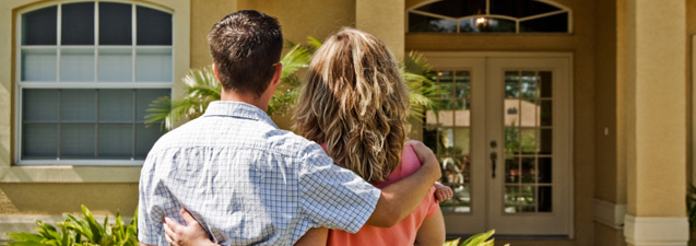 A family couple standing outside their home